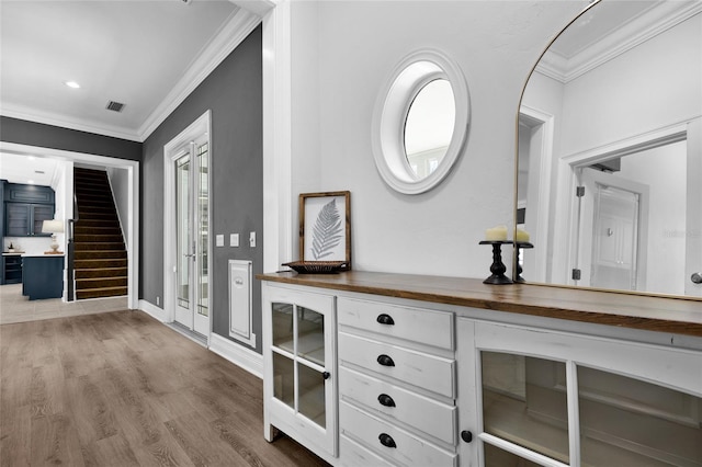 interior space featuring baseboards, visible vents, wood finished floors, stairs, and crown molding