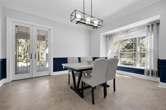 dining room with an inviting chandelier, light tile patterned floors, ornamental molding, and french doors