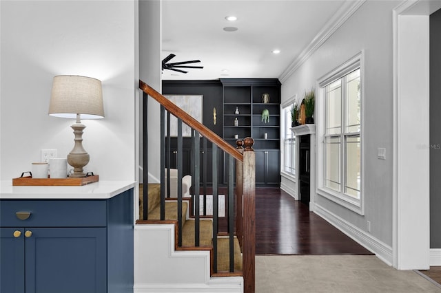 interior space with baseboards, ceiling fan, stairway, ornamental molding, and wood finished floors