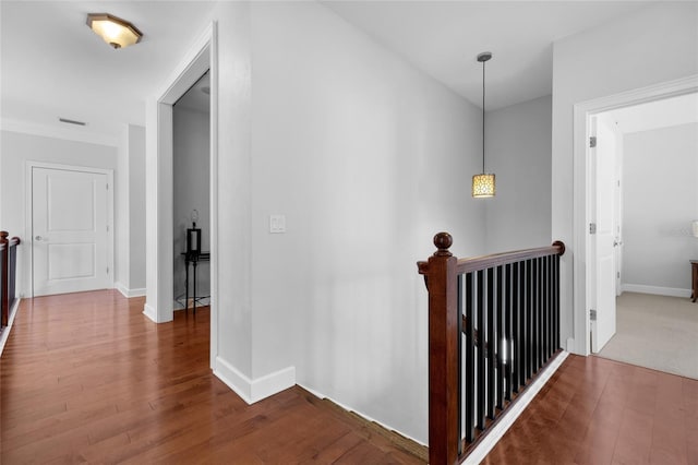 hallway featuring wood finished floors, an upstairs landing, and baseboards