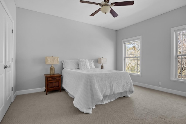 bedroom featuring a closet, baseboards, a ceiling fan, and light colored carpet