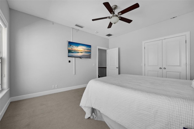 carpeted bedroom featuring a ceiling fan, a closet, visible vents, and baseboards