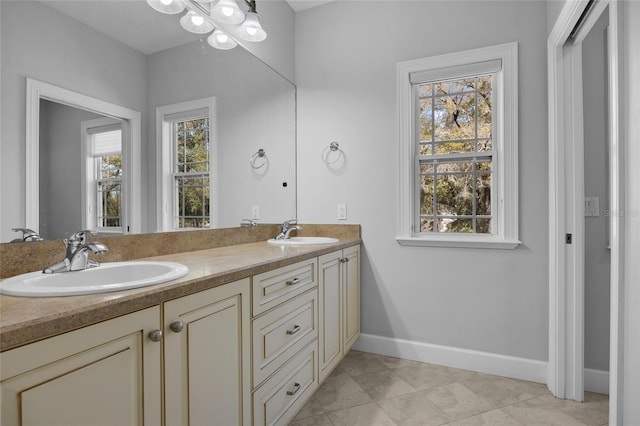 full bath featuring double vanity, a wealth of natural light, baseboards, and a sink