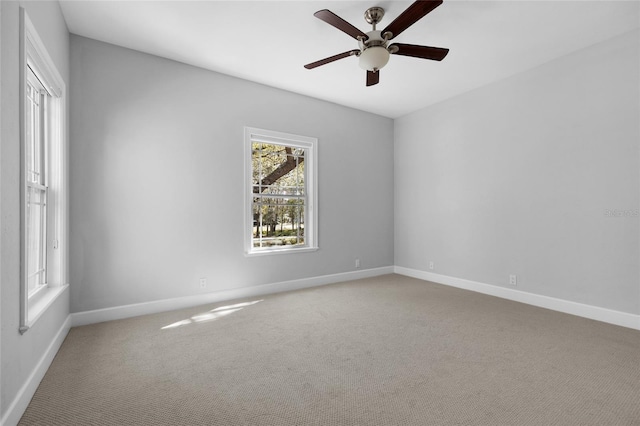 carpeted empty room with a ceiling fan and baseboards