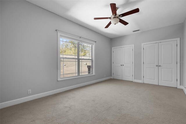 unfurnished bedroom with carpet floors, baseboards, visible vents, and multiple closets