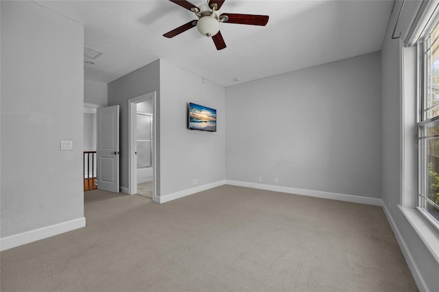 empty room with baseboards, a ceiling fan, and light colored carpet