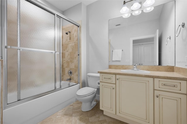 bathroom featuring bath / shower combo with glass door, vanity, tile patterned flooring, and toilet