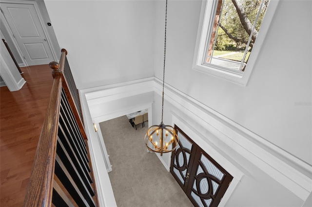 staircase with wood finished floors and an inviting chandelier