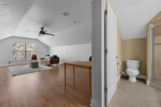 additional living space featuring lofted ceiling, a textured ceiling, light wood-type flooring, and baseboards