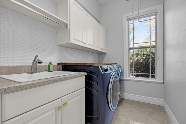 washroom featuring cabinet space, baseboards, washer and clothes dryer, and a sink