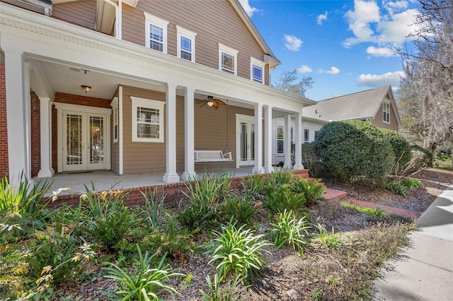 entrance to property featuring covered porch, brick siding, and french doors