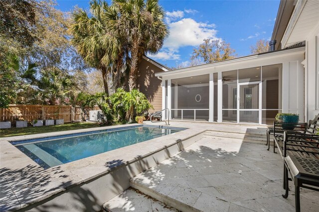 view of pool featuring a sunroom, fence, and a patio