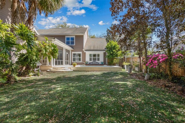 rear view of property with a sunroom, a fenced backyard, and a yard