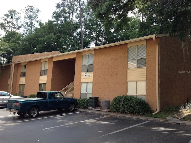 view of building exterior with uncovered parking and central AC