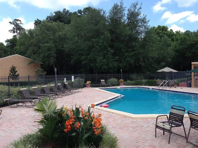 community pool with fence and a patio