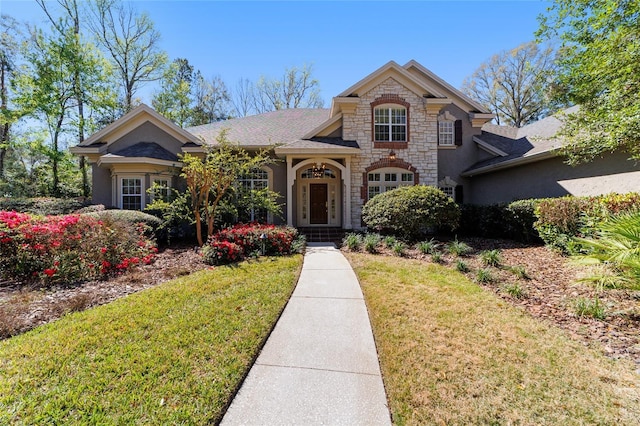 view of front of property with stucco siding, stone siding, and a front yard