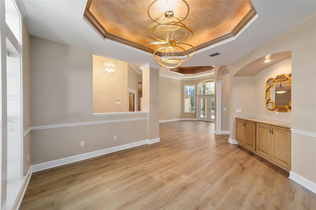 interior space with light wood-style flooring, baseboards, and a tray ceiling