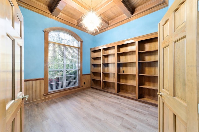 empty room with a wainscoted wall, beamed ceiling, light wood-type flooring, and ornamental molding