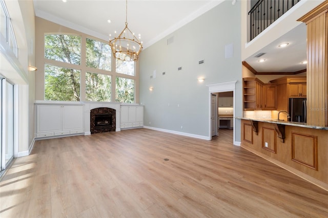 unfurnished living room with ornamental molding, light wood-style floors, baseboards, and a premium fireplace