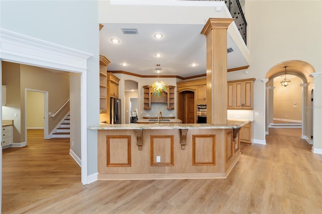 kitchen featuring visible vents, open shelves, stainless steel fridge with ice dispenser, arched walkways, and a kitchen bar