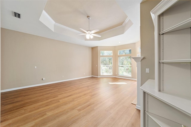 unfurnished living room featuring a ceiling fan, visible vents, crown molding, a raised ceiling, and light wood-type flooring