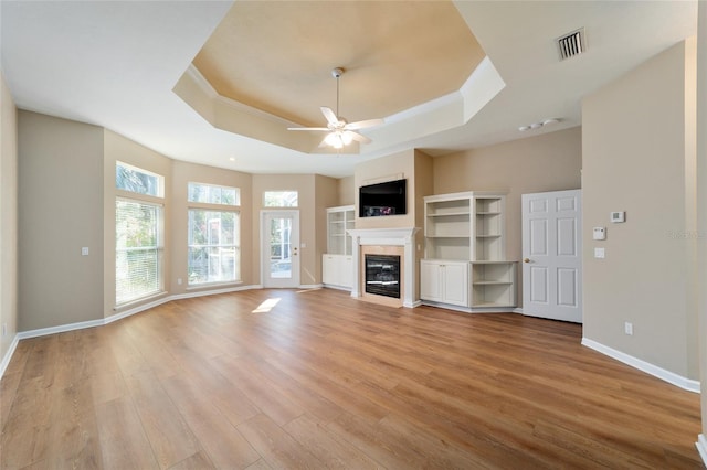 unfurnished living room featuring visible vents, a fireplace with flush hearth, ceiling fan, a raised ceiling, and light wood-type flooring