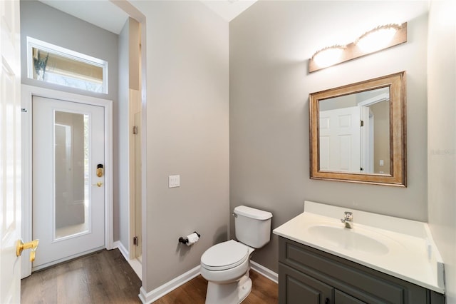 bathroom with toilet, vanity, baseboards, and wood finished floors