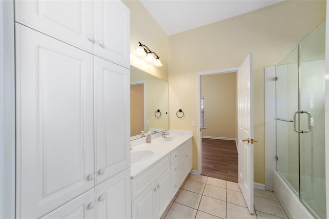 full bath featuring tile patterned flooring, double vanity, baseboards, and a sink