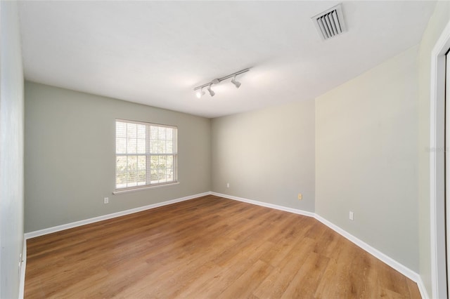 empty room with visible vents, baseboards, light wood-style floors, and rail lighting