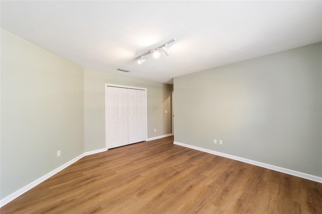 spare room with track lighting, light wood-style floors, visible vents, and baseboards