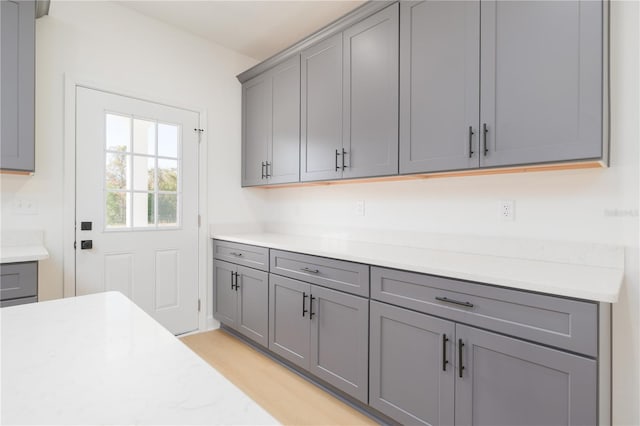 kitchen with light wood-type flooring, gray cabinets, and light countertops