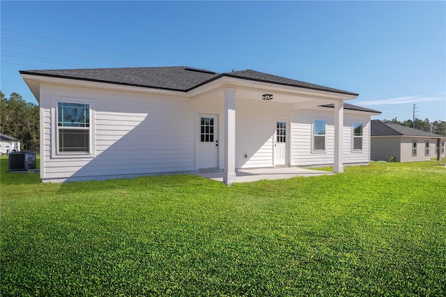 rear view of property with a yard, roof with shingles, a patio area, and central air condition unit