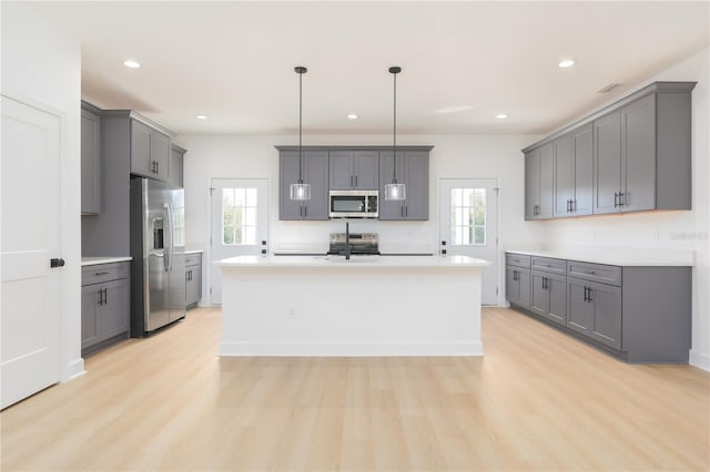 kitchen with light wood finished floors, light countertops, appliances with stainless steel finishes, and gray cabinetry