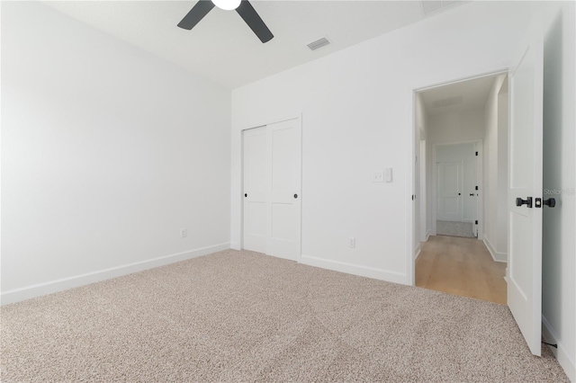 unfurnished bedroom featuring a closet, visible vents, light carpet, ceiling fan, and baseboards