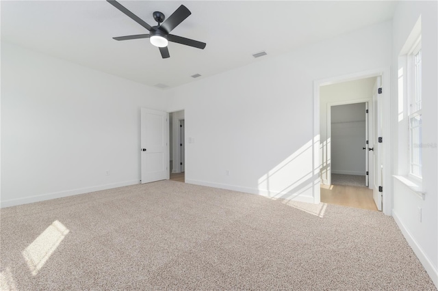 spare room featuring light colored carpet, visible vents, and baseboards