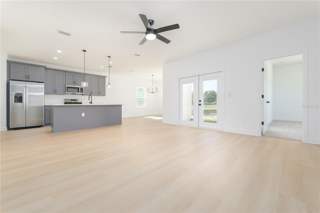 unfurnished living room with french doors, light wood finished floors, recessed lighting, visible vents, and ceiling fan with notable chandelier