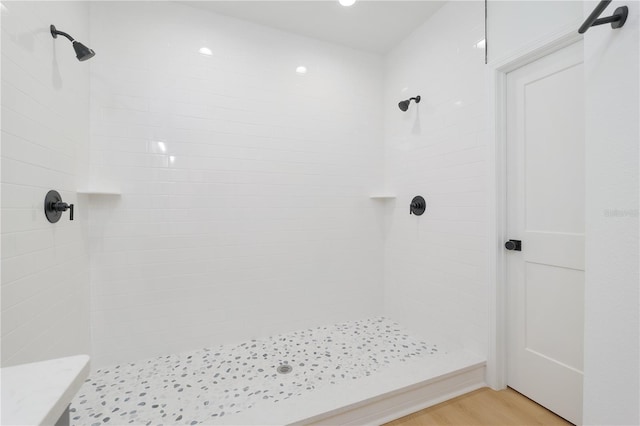 bathroom with tiled shower and wood finished floors