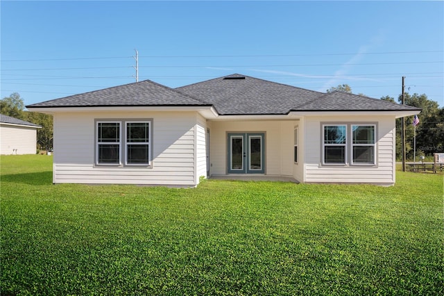 rear view of house featuring french doors, roof with shingles, and a yard