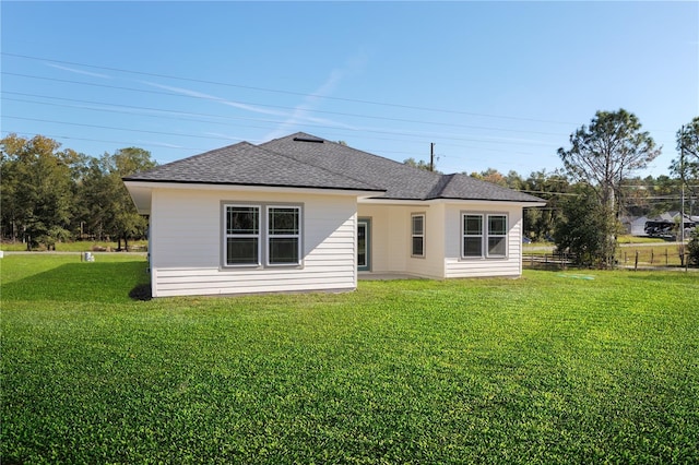 rear view of house featuring a yard and roof with shingles