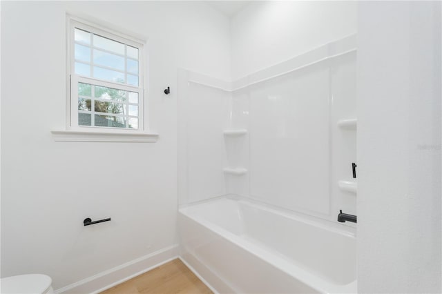 bathroom featuring bathtub / shower combination, wood finished floors, toilet, and baseboards