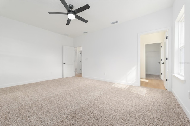 unfurnished room featuring a ceiling fan, light colored carpet, visible vents, and baseboards