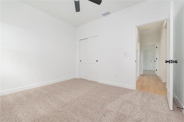 unfurnished bedroom featuring light carpet, a closet, visible vents, and baseboards