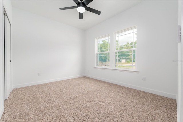 carpeted spare room with ceiling fan and baseboards