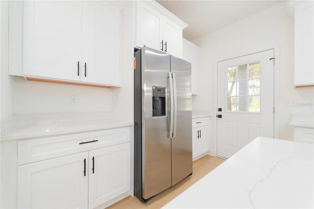 kitchen featuring light wood-style flooring, stainless steel refrigerator with ice dispenser, light stone countertops, and white cabinets