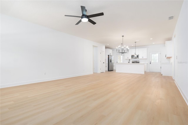 unfurnished living room with light wood finished floors, baseboards, visible vents, and ceiling fan with notable chandelier