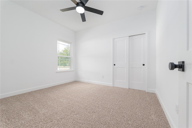 carpeted spare room featuring a ceiling fan and baseboards