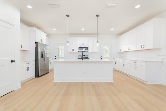 kitchen featuring light wood finished floors, stainless steel appliances, recessed lighting, light countertops, and white cabinetry