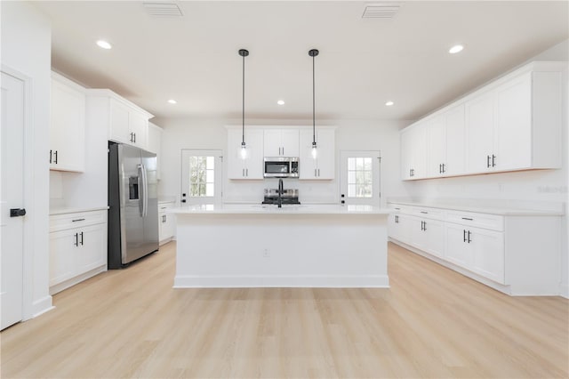 kitchen featuring visible vents, appliances with stainless steel finishes, light countertops, light wood-style floors, and white cabinetry