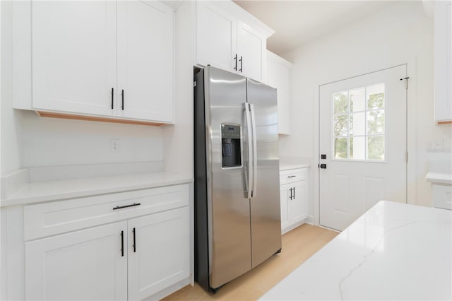 kitchen with light wood-style flooring, light stone countertops, white cabinetry, and stainless steel fridge with ice dispenser