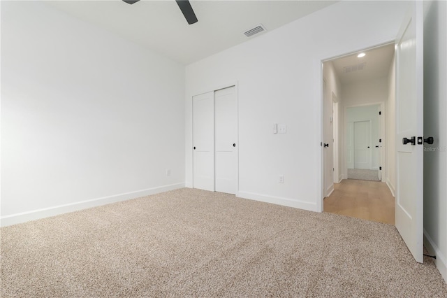 unfurnished bedroom with baseboards, visible vents, a closet, and light colored carpet